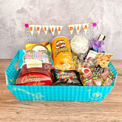 La cesta de regalo Regalo Full Feliz incluye aperitivos variados (aros, caramelos, bombones y un zumo en caja) con una pancarta 