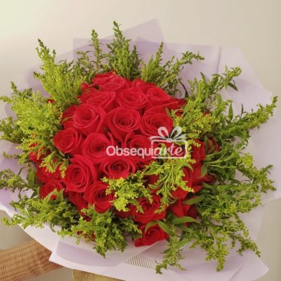 Un Gran Bouquet con 48 Rosas rojas rodeadas de vegetación, envueltas en papel blanco.