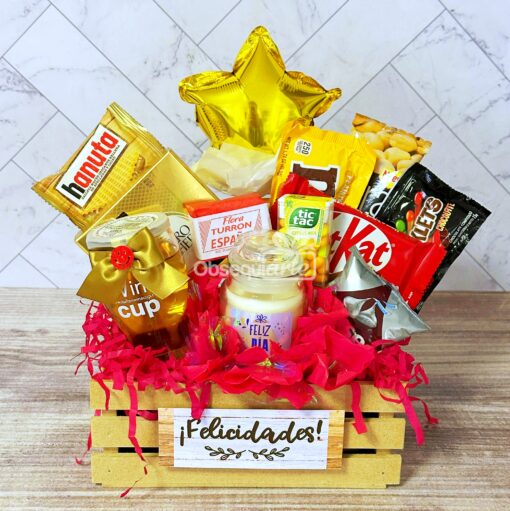 La canasta de madera para regalo Regalo Primavera con Vela y Vino incluye deliciosos bocadillos, un alegre globo con forma de estrella amarilla y adornos festivos. Un cartel que dice "¡Felicidades!" le agrega un toque alegre a la celebración de la temporada.