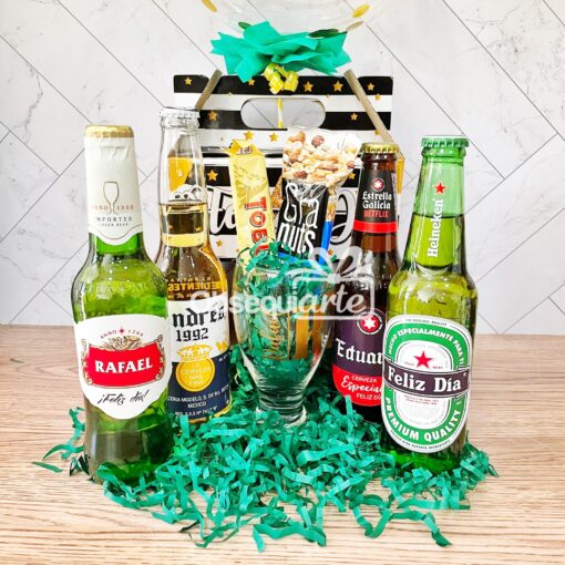 Una cesta de regalo Regalo Perfect Pack con botellas de cerveza y oropel verde.