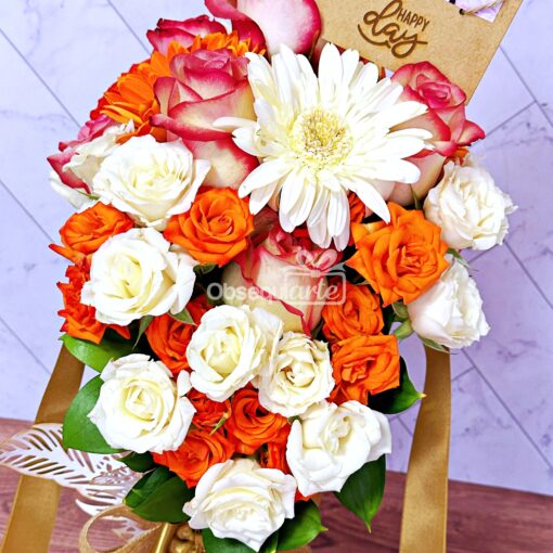 Un vibrante arreglo de Arreglo Cono Flowers de rosas naranjas y blancas con una gerbera, acompañado de una nota de "feliz día".