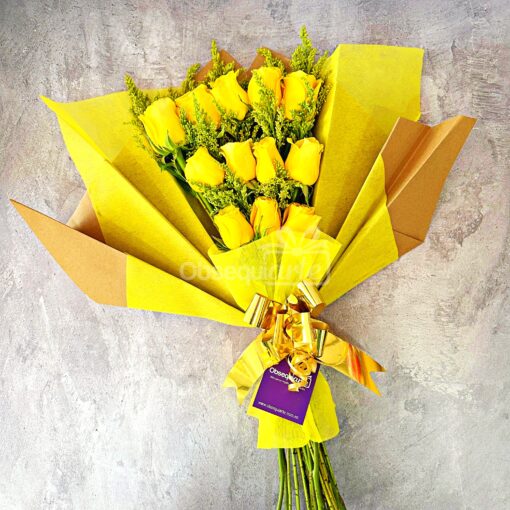 Un Ramo de Rosas envuelto en papel amarillo con una cinta decorativa y una etiqueta de regalo.