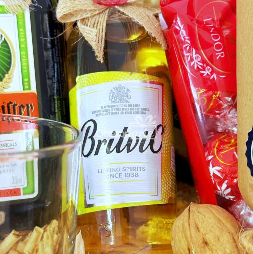 La caja Regalo Élite incluye una botella de agua tónica Britvic elegantemente rodeada de una selección selecta de alimentos: una caja de bombones, un paquete de galletas y nueces, creando el regalo perfecto.