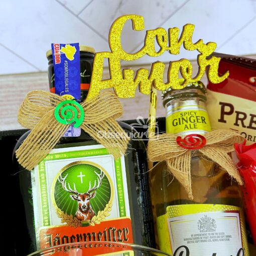 La caja Regalo Élite incluye una canasta de regalo cuidadosamente seleccionada que contiene Jägermeister, ginger ale, chocolates variados y un encantador cartel decorativo con el mensaje "Con Amor".