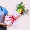 Una persona sostiene el vibrante Ramo de Flores Brisa de Alegría, elegantemente envuelto en papel rosa y atado con una alegre cinta roja.