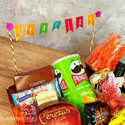 La cesta de regalo Regalo Full Feliz, repleta de aperitivos como Pringles, Ferrero Rocher y bombones, además de una vibrante pancarta de 