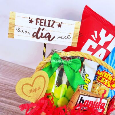 Una canasta de regalo llena de bocadillos, una botella de dulces verde, un letrero de 