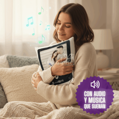 Una mujer sentada en una cama abraza un Regalo Almohada Musical con una foto impresa y notas musicales. Una insignia en español dice: 