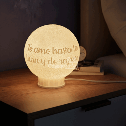 El Regalo Lámpara 3D Moon Personalizada con "Te amo hasta la luna y de regreso" se asienta sobre una mesilla de noche de madera junto a un reloj y un libro, lo que lo convierte en el regalo perfecto para alguien especial.