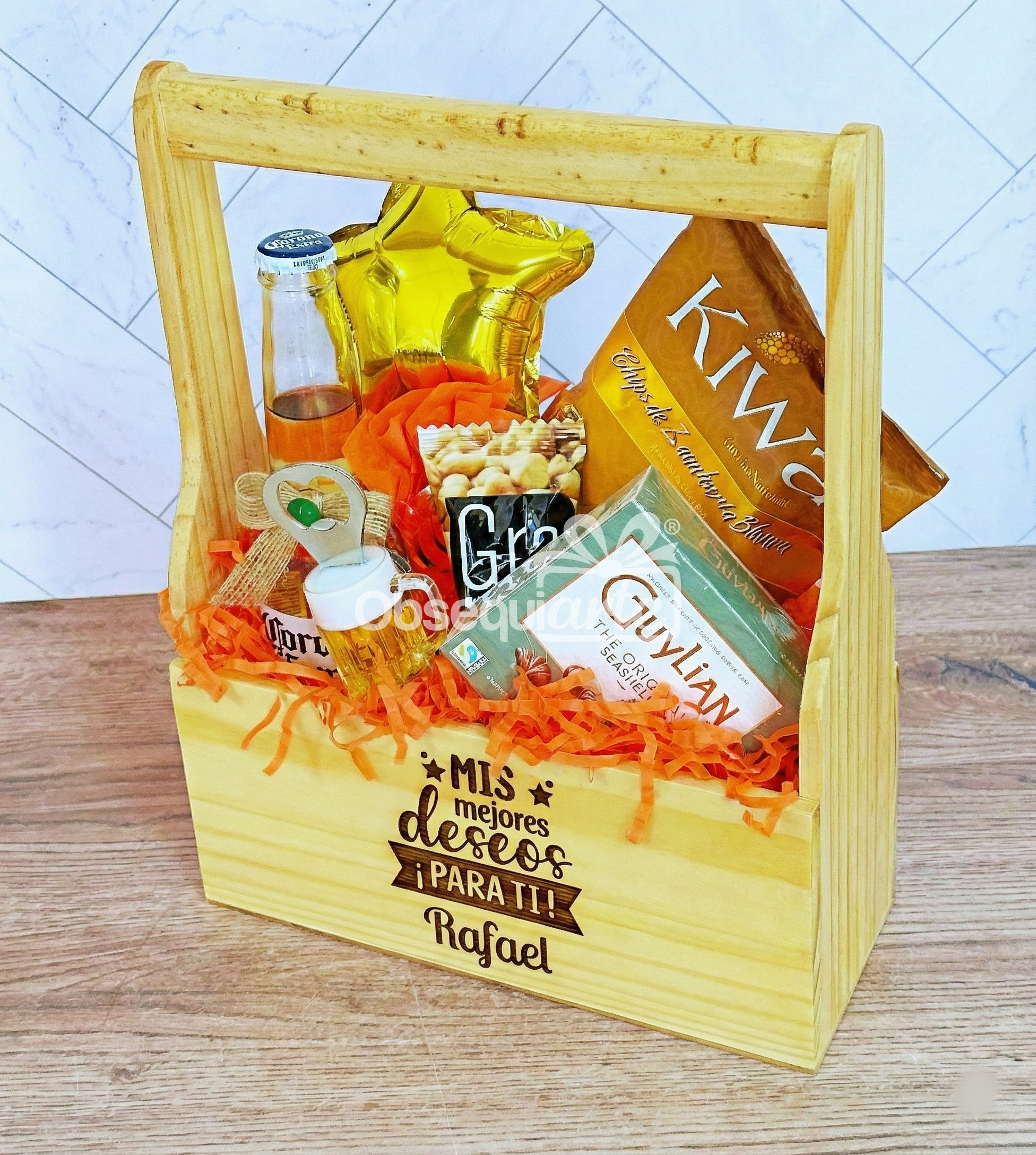 Regalo Jaba Personal: Caja de regalo de madera con aperitivos variados, mini botella, globo estrella dorado, papel picado naranja y tu mensaje personalizado grabado en la parte delantera.