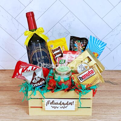 Caja de regalo Regalo Diamond con vino tinto, bombones variados, galletas y aperitivos, decorada con un lazo amarillo y un letrero 