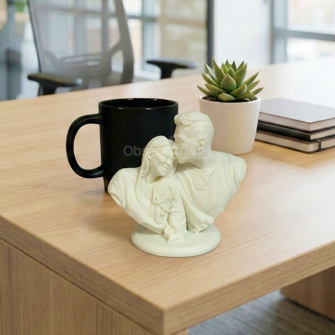 Un Regalo Eternal Love estatua busto personalizado (blanco), una taza negra, una suculenta maceta y dos cuadernos están dispuestos sobre un escritorio de madera clara en un entorno de oficina.