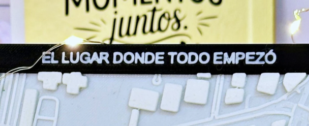 Cartel con la frase en español "EL LUGAR DONDE TODO EMPEZÓ" en letras blancas, delante de un fondo amarillo con texto parcialmente visible.