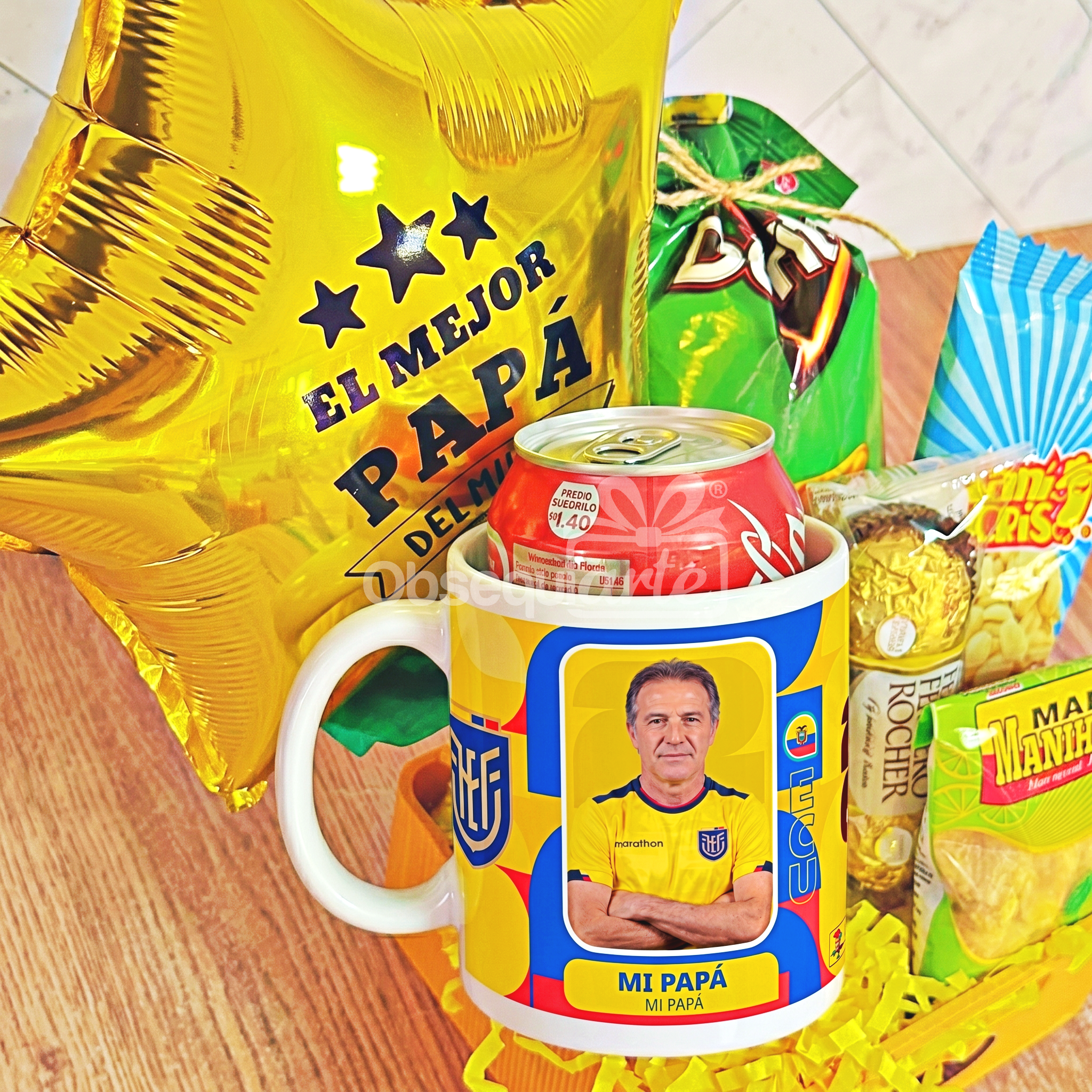 El «Regalo Papá Mundialista» incluye un globo amarillo con el mensaje «El Mejor Papá», una lata de refresco roja, aperitivos y una taza con la imagen de un «Mundialista» vestido con la camiseta de la selección de fútbol de Ecuador y el texto «Mi Papá», ideal para cualquier ocasión especial.