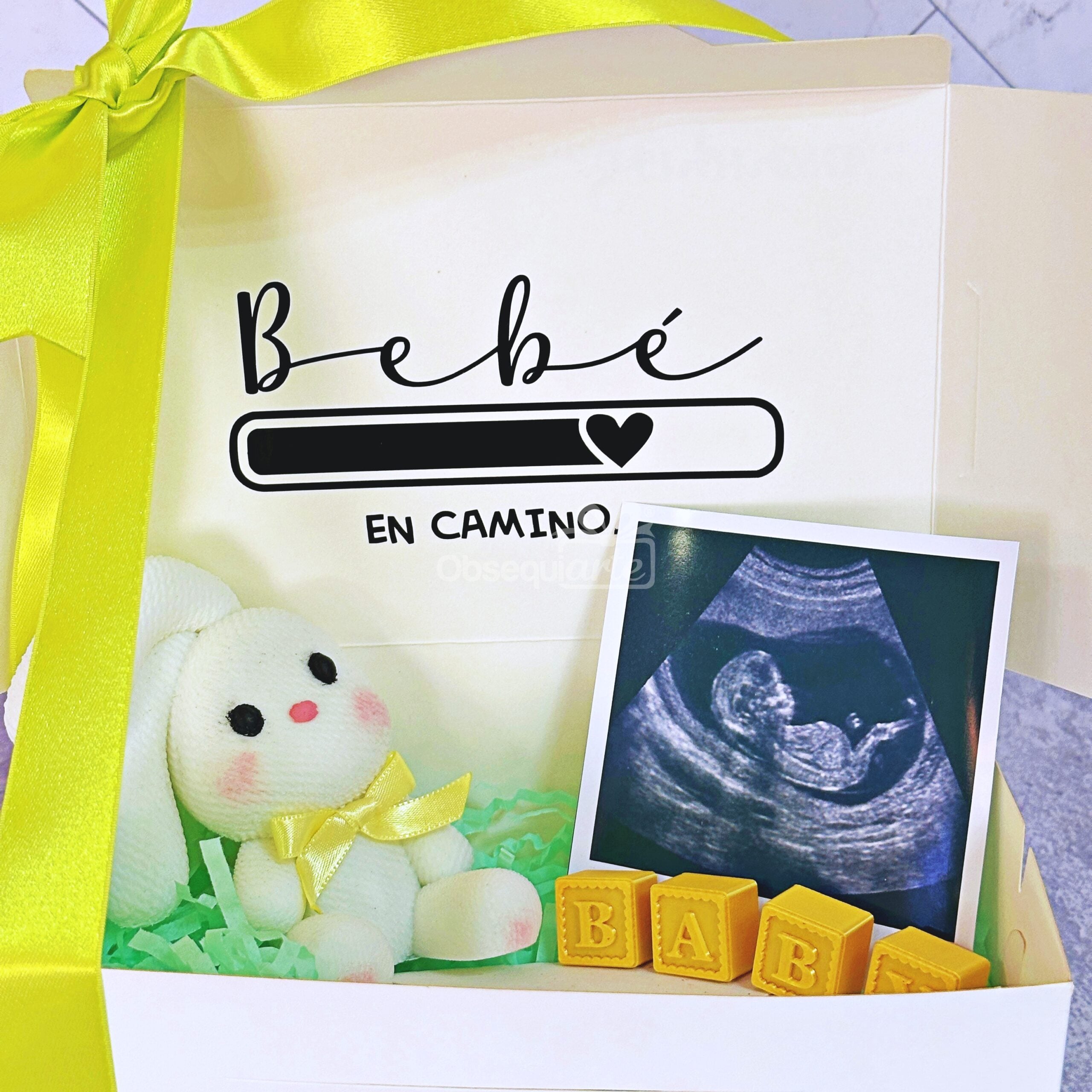 Celebra este momento tan especial con la caja de regalo «Regalo Bebé en Camino», que incluye un conejito de peluche, una cinta amarilla, bloques de juguete que forman la palabra «BABY» y una ecografía. En la tapa de la caja se lee «Bebé en camino» junto a un símbolo de corazón, lo que la convierte en un adorable regalo para las familias que esperan un bebé.