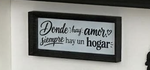 Cartel rectangular para colgar en la pared en el que se lee: «Donde hay amor, siempre hay un hogar».